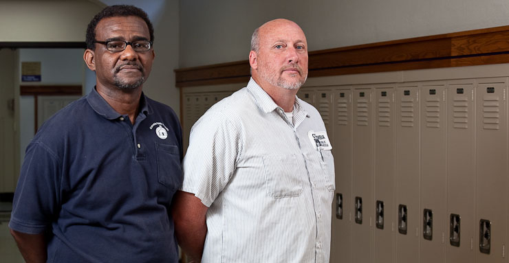 Anthony Fitzgerald, left, a Hickman High School custodian, and Arnold Cromwell, right, a custodian from Rock Bridge High School, stand in the hallways of Hickman High on Monday, September 21, 2009 in Columbia, Mo.  Despite the two schools' athletic rivalries, neither Fitzgerald or Cromwell take it too seriously.